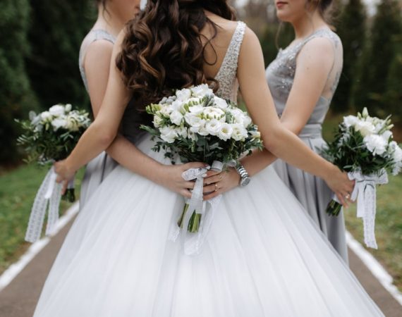 back-bride-bridesmaids-with-white-eustoma-wedding-bouquets-outdoors-min