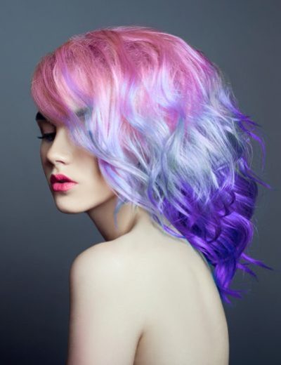 Portrait of a woman with bright colored flying hair, all shades of purple. Hair coloring, beautiful lips and makeup. Hair fluttering in the wind. Sexy girl with short  hair. Professional coloring